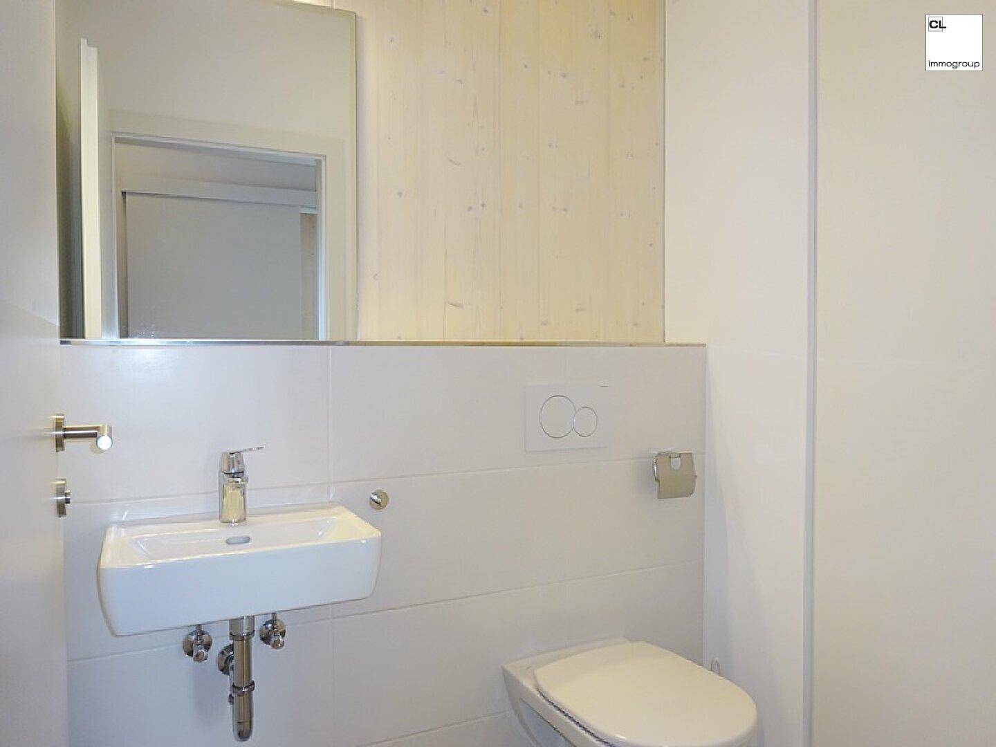 Modernes Gäste-WC mit wandhängendem WC und kleinem Waschbecken.