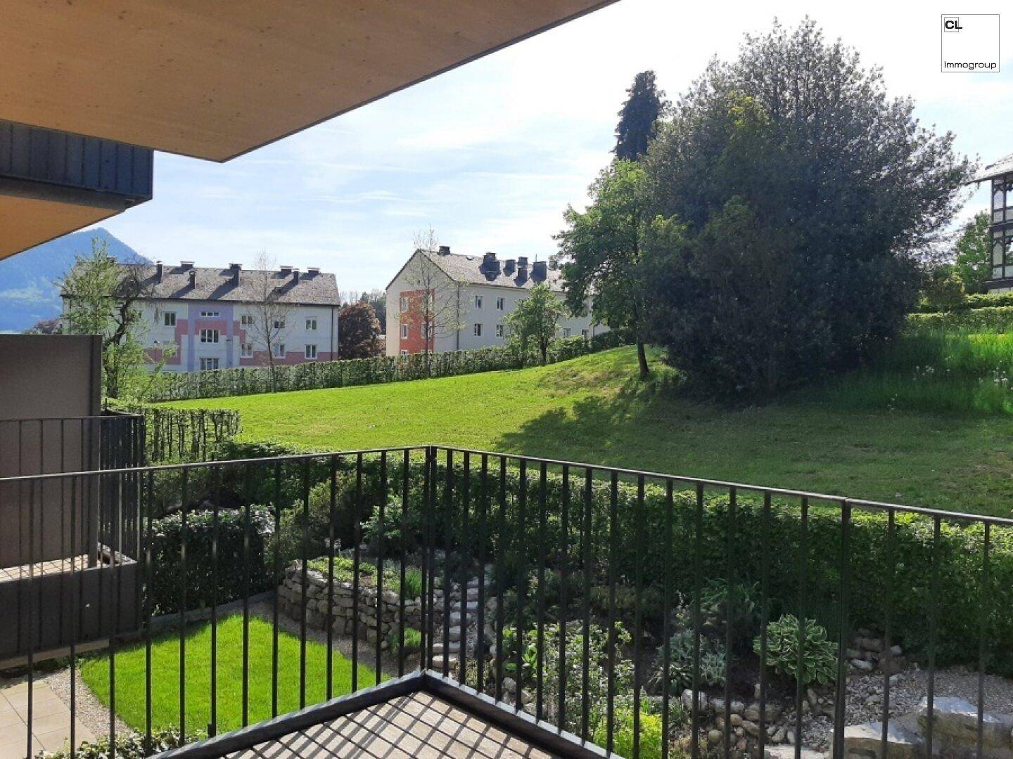 Balkon mit weitem Blick auf eine gepflegte Grünfläche und weitere Wohnhäuser.