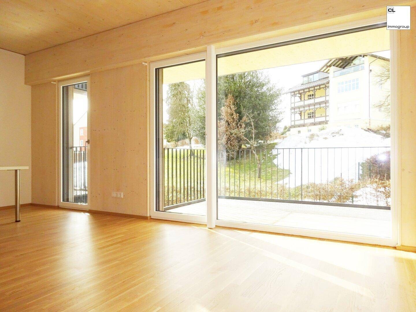 Heller Wohnbereich mit großen Schiebetüren, Holzboden und Zugang zu einem Außenbereich.