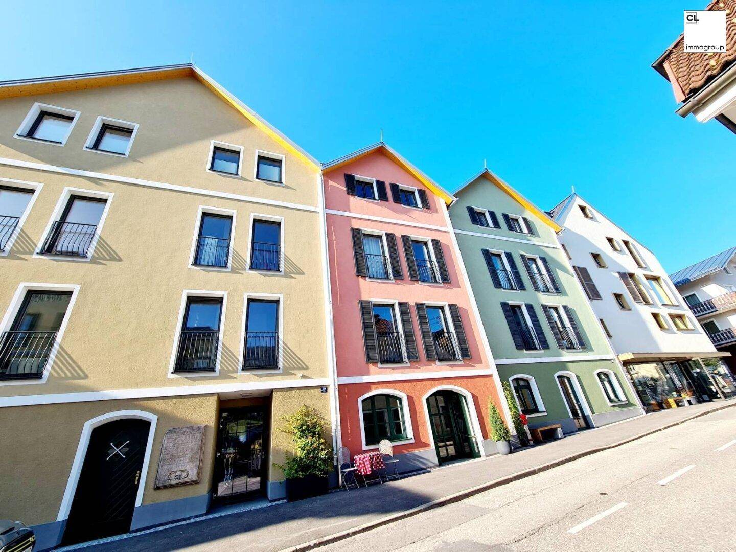 Reihe von farbenfrohen Stadthäusern mit traditionellen Giebeldächern und Balkonen.