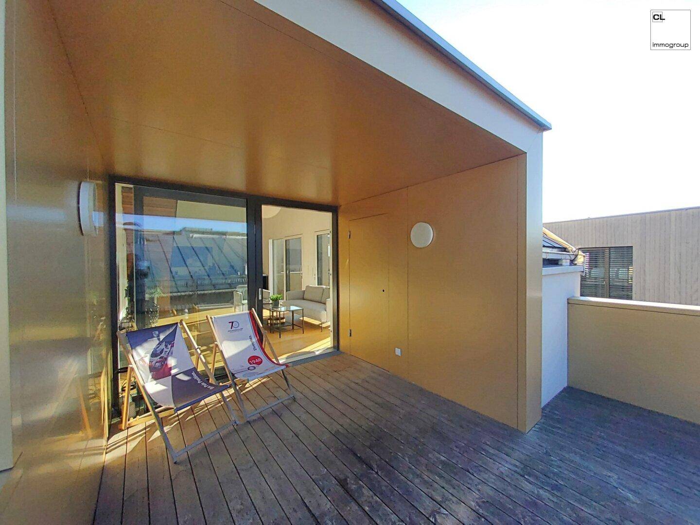 Geräumige Holzterrasse mit Sonnenliegen und direktem Zugang zum Wohnbereich.