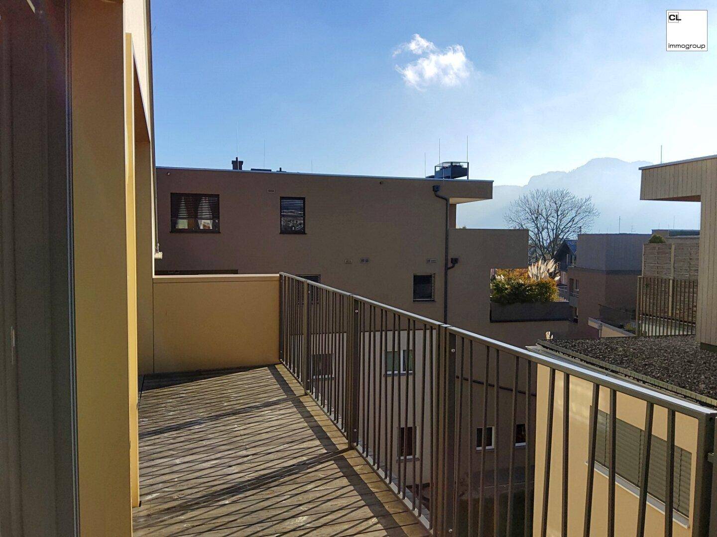 Sonniger Balkon mit Metallgeländer und weitem Blick auf die umliegende Landschaft und Berge.