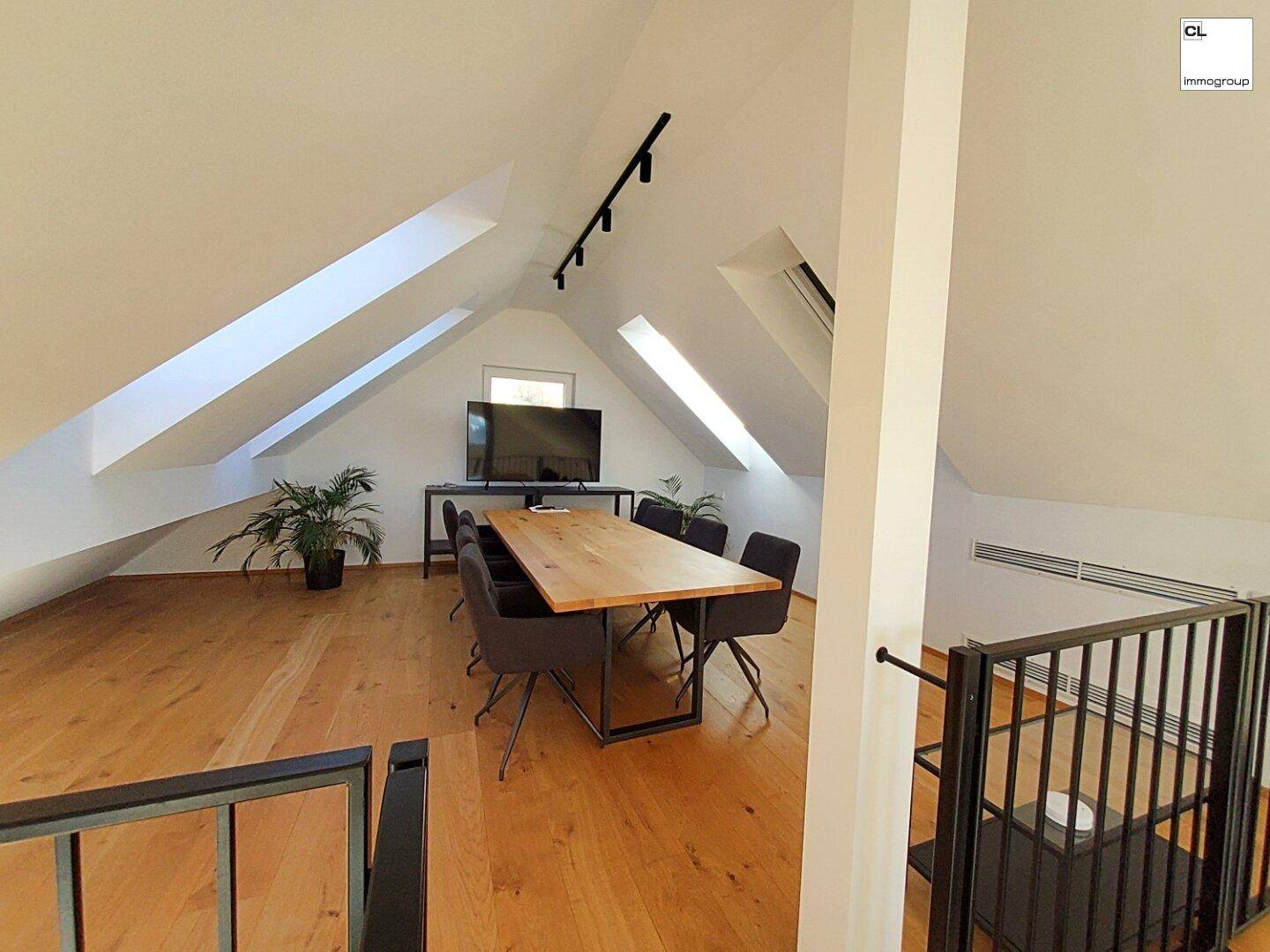Geräumiger Essbereich im Dachgeschoss mit Holzboden, Dachschrägen und großen Fenstern.