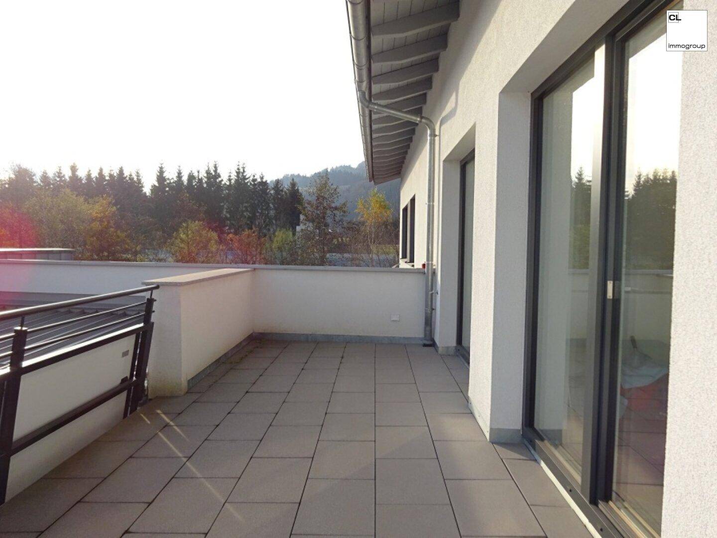 Großer Balkon mit Fliesenboden und weitem Blick auf die umliegende Natur und bewaldete Hügel.