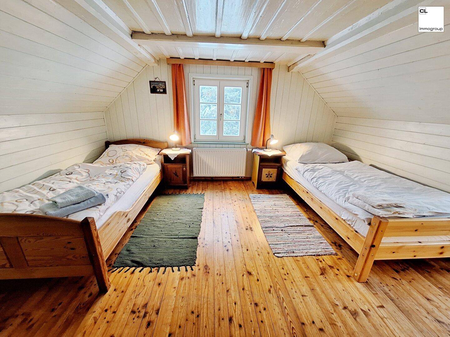 Gemütliches Schlafzimmer mit zwei Einzelbetten, Holzboden und Dachschrägen.
