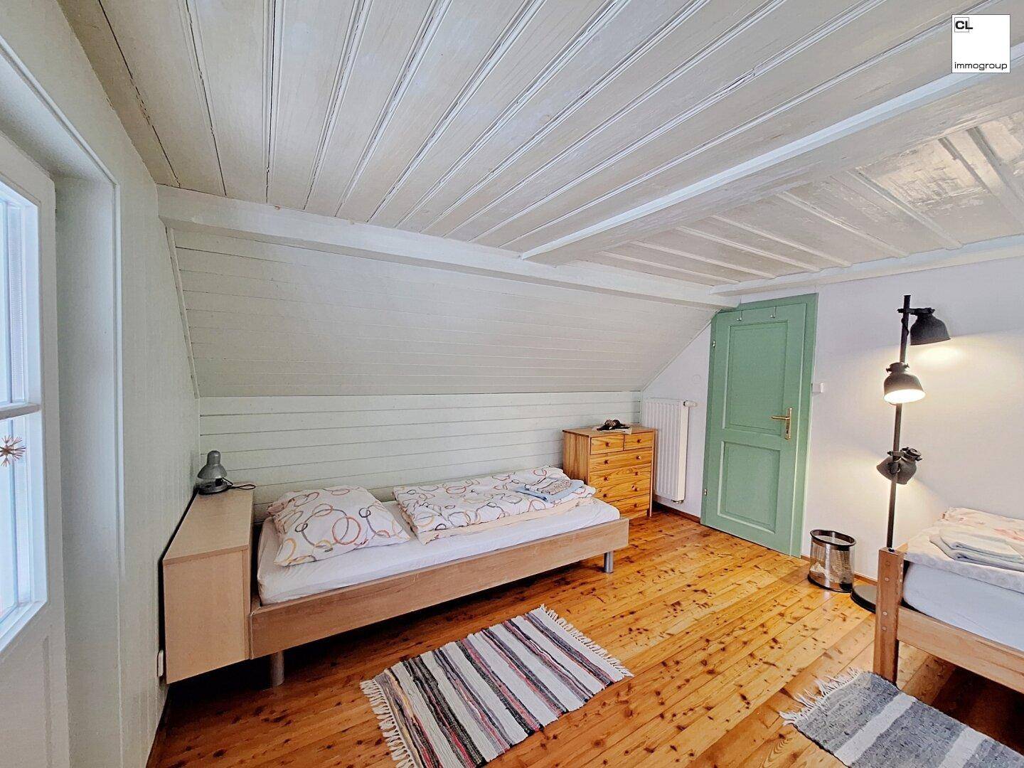 Helles Schlafzimmer mit Einzelbett, Holzboden und Dachschrägen in rustikalem Ambiente.