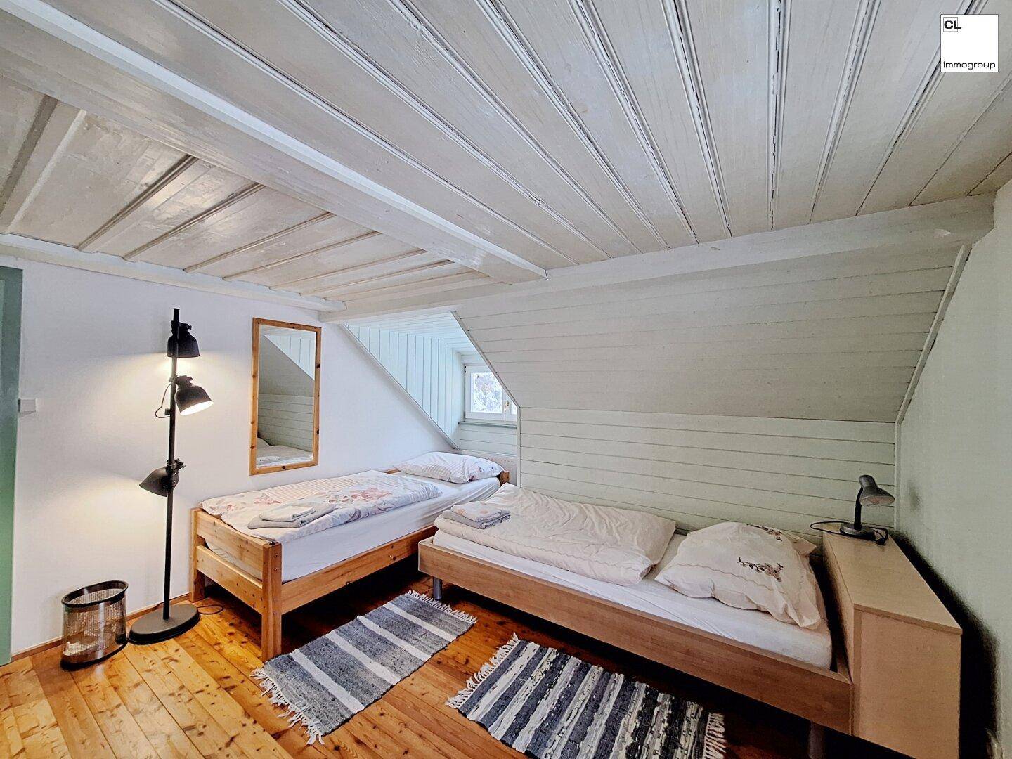 Geräumiges Schlafzimmer mit zwei Einzelbetten, Holzboden und Dachschrägen.