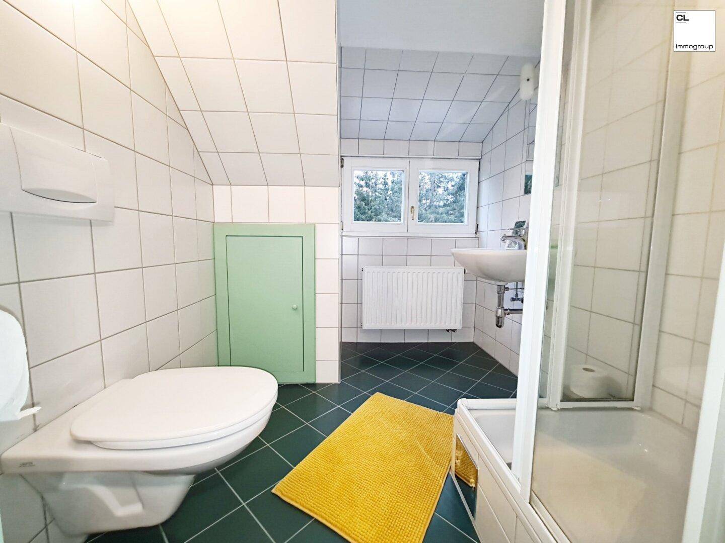Modernes Badezimmer mit Dusche, weißen Fliesen und Dachschräge.