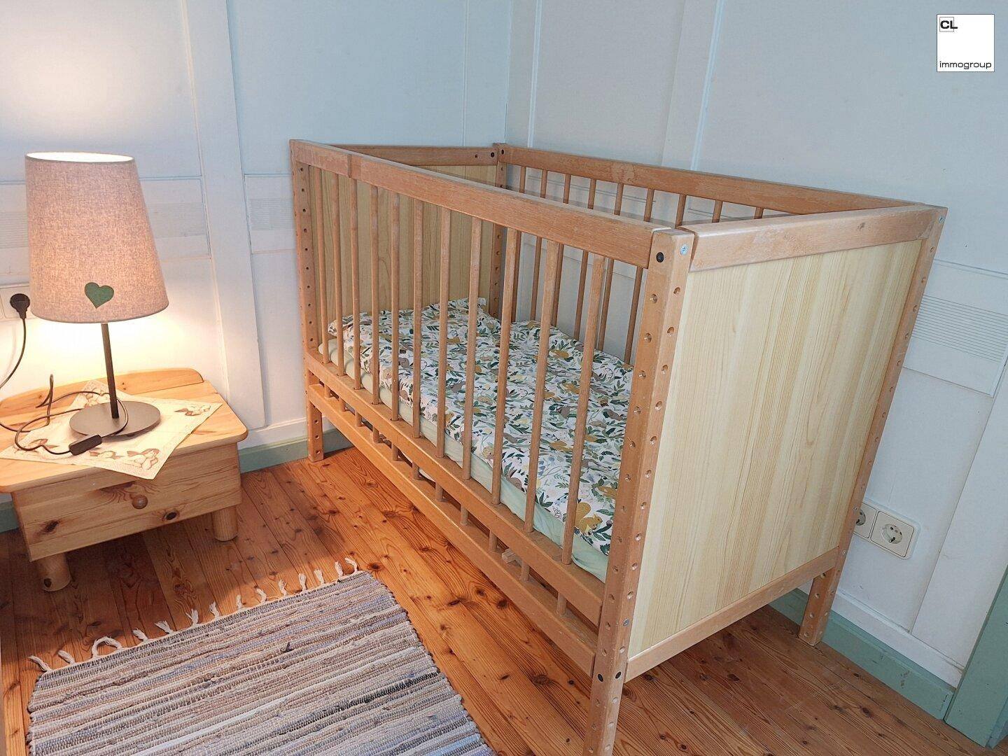 Detailansicht eines Babybetts aus hellem Holz im gemütlichen Schlafzimmer.