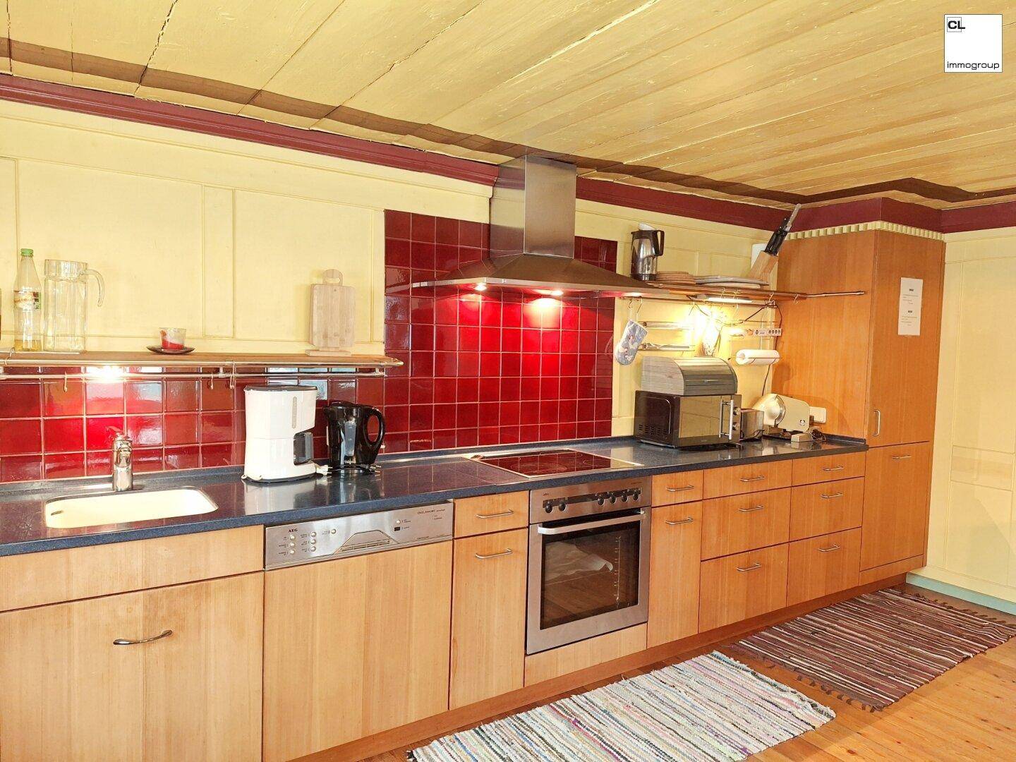 Geräumige Küche mit Holzfronten, rotem Fliesenspiegel und praktischer Arbeitsfläche.