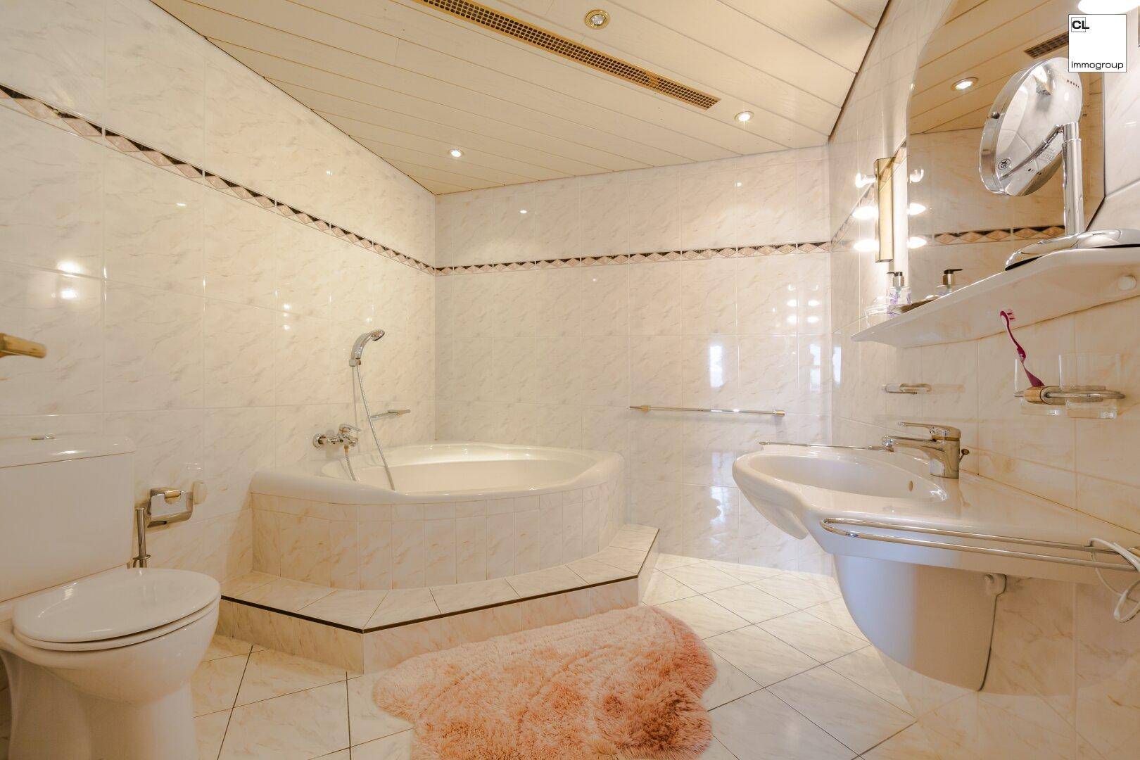 Helles Badezimmer mit Eckbadewanne, WC und Waschbecken, ausgestattet mit weißen Fliesen.