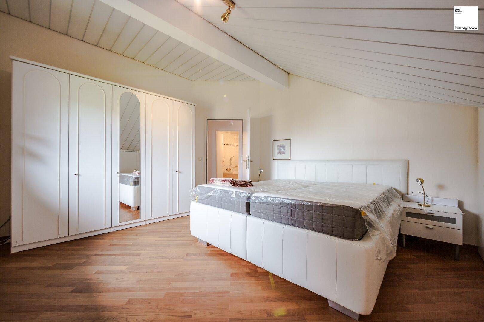 Geräumiges Schlafzimmer im Dachgeschoss mit Holzboden und großem Kleiderschrank.