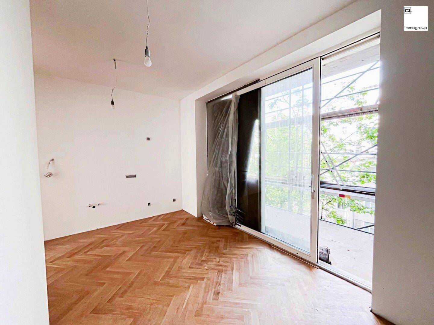 Geräumiges Zimmer mit Fischgrätparkett und großer Schiebetür zum Außenbereich.