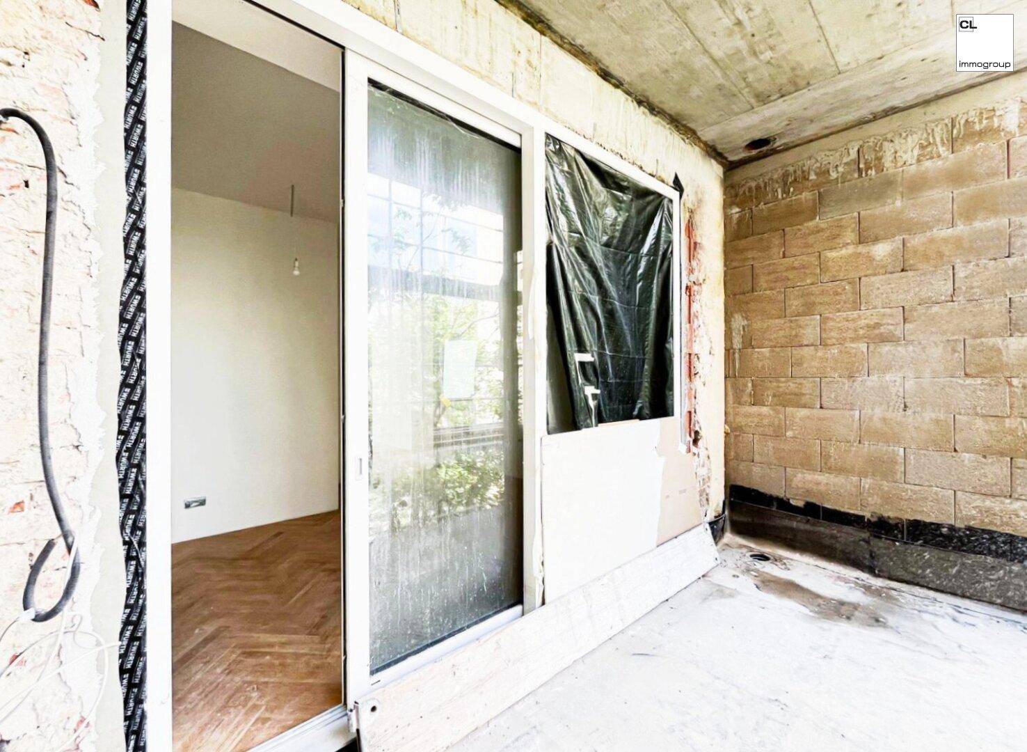 Unfertiger Balkon mit Betonboden und Ziegelwand, mit Zugang zum Innenraum.