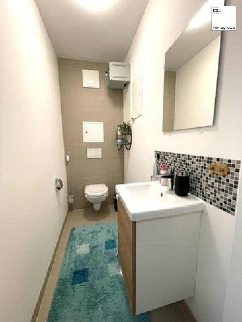 Kleines Gäste-WC mit modernem Waschbecken und Wandfliesen in neutralen Farbtönen.