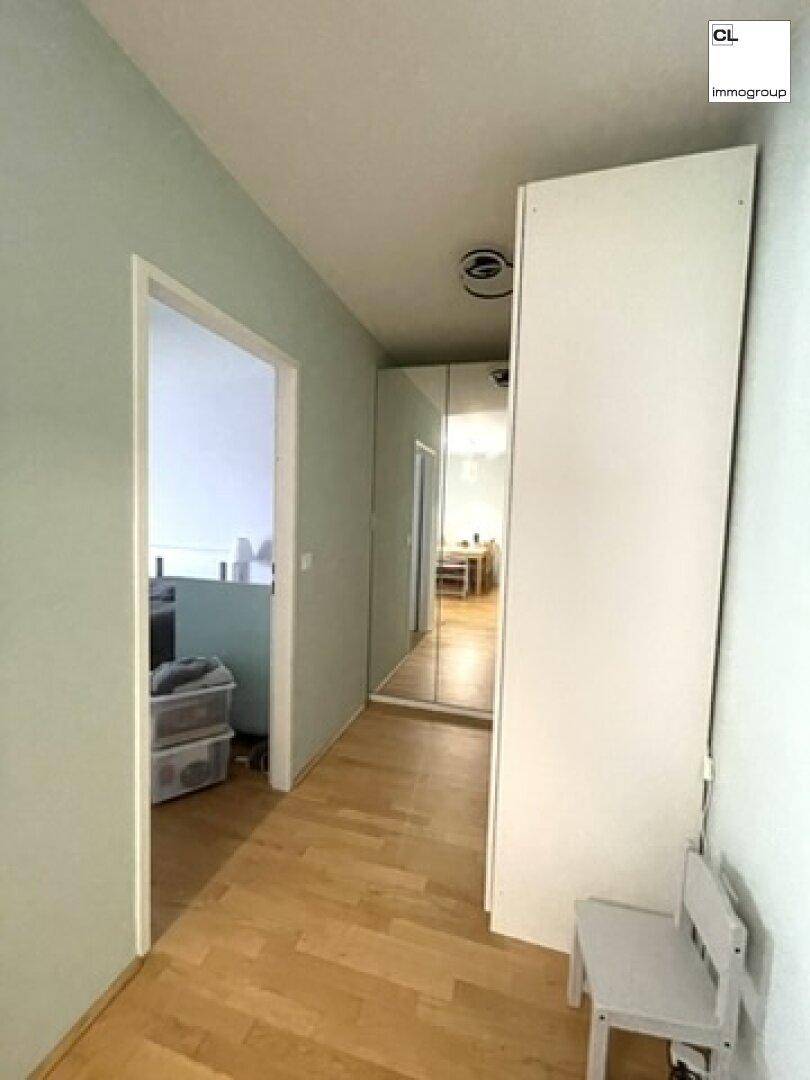 Heller Flur mit Holzboden und einem großen Spiegel, der den Raum optisch erweitert.