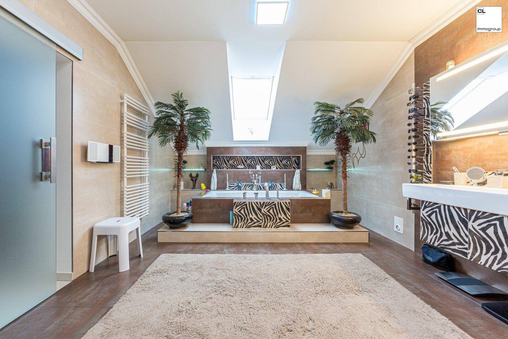 Modernes Badezimmer mit Badewanne, Doppelwaschbecken und exotischer Dekoration unter Dachschrägen.
