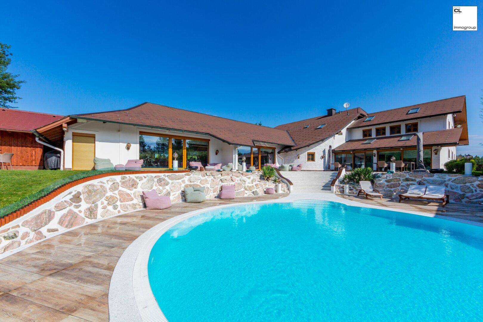 Elegantes Anwesen mit großem Pool, Steinfassade und weitläufigem Gartenbereich.