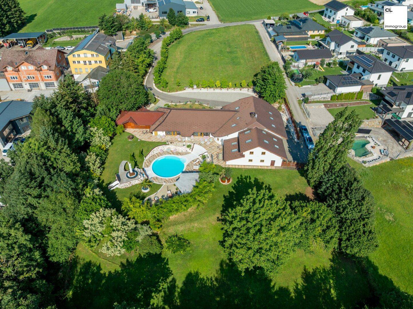 Luftaufnahme des weitläufigen Anwesens mit großem Garten, Pool und umliegender Landschaft.
