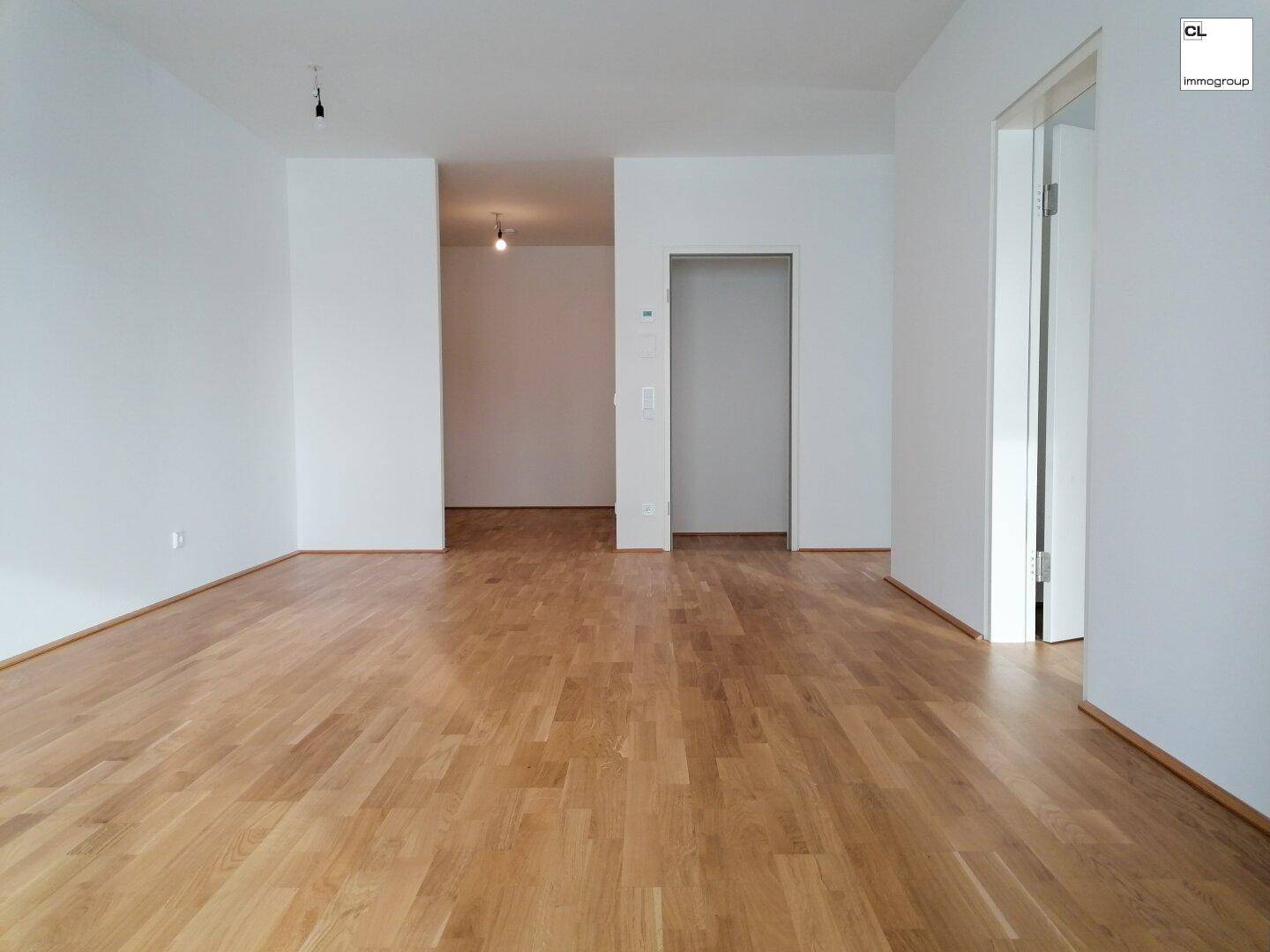 Heller, leerer Raum mit neuem Laminatboden und weißen Wänden, bereit zum Einzug.