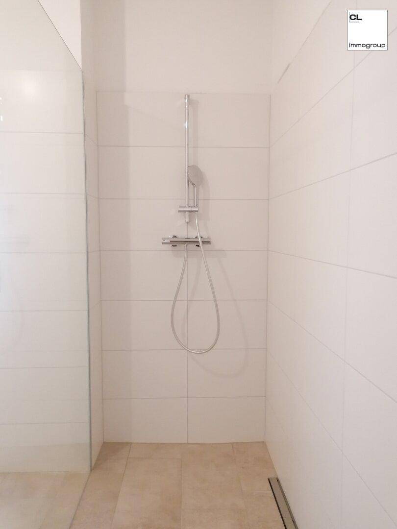 Moderne begehbare Dusche mit weißen Fliesen und minimalistischem Design im Badezimmer.