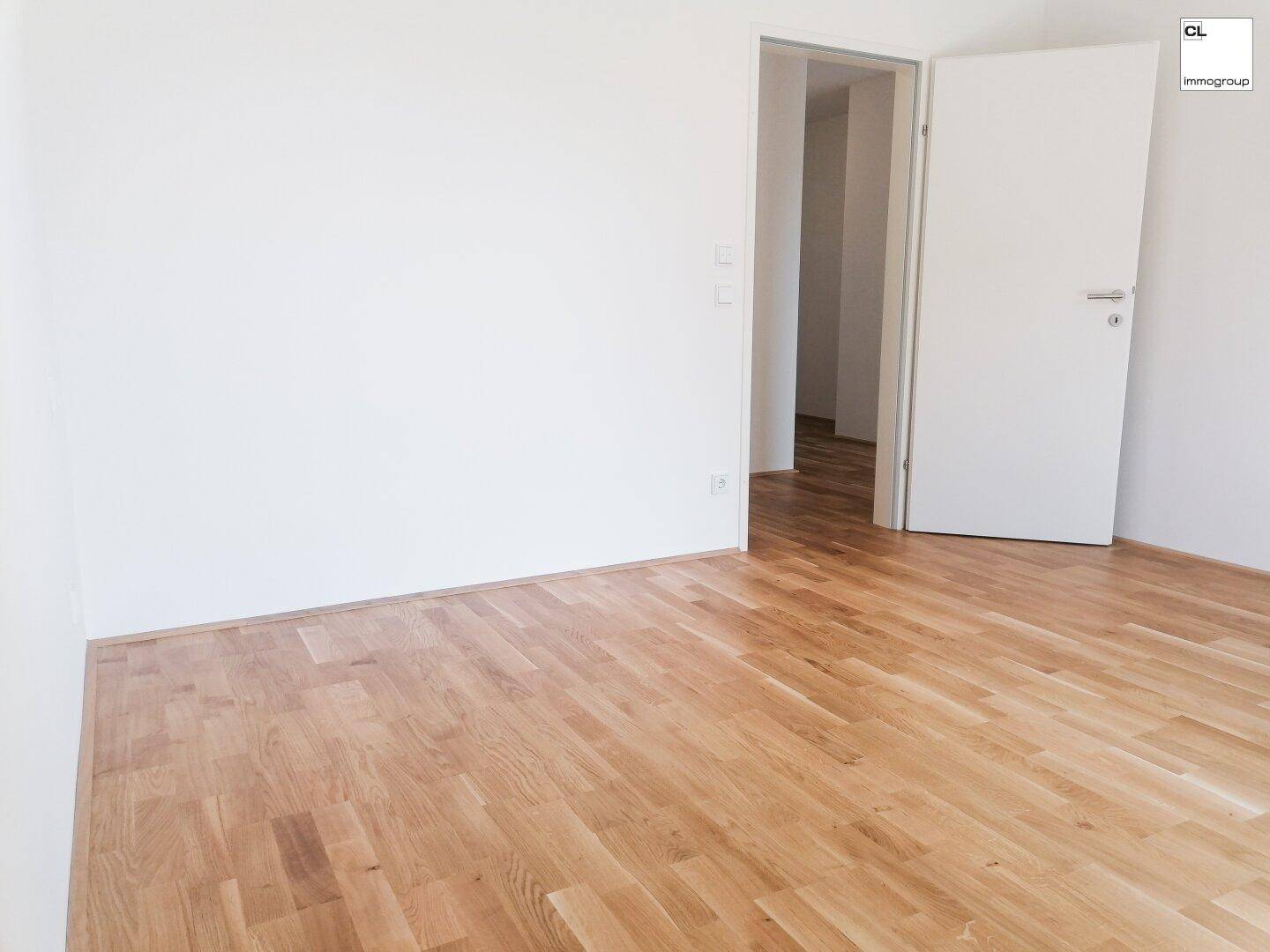 Leeres Zimmer mit hellem Parkettboden und weißen Wänden, bereit zur individuellen Gestaltung.