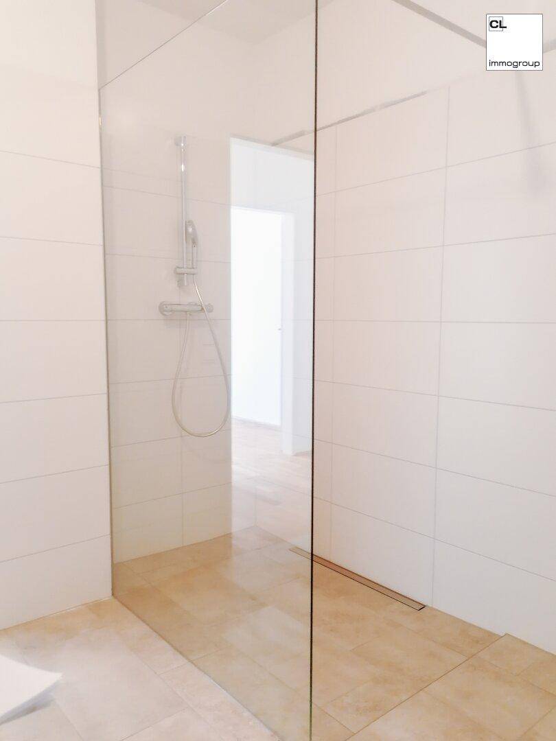 Geräumige begehbare Dusche mit Glasabtrennung und hellen Fliesen im modernen Badezimmer.
