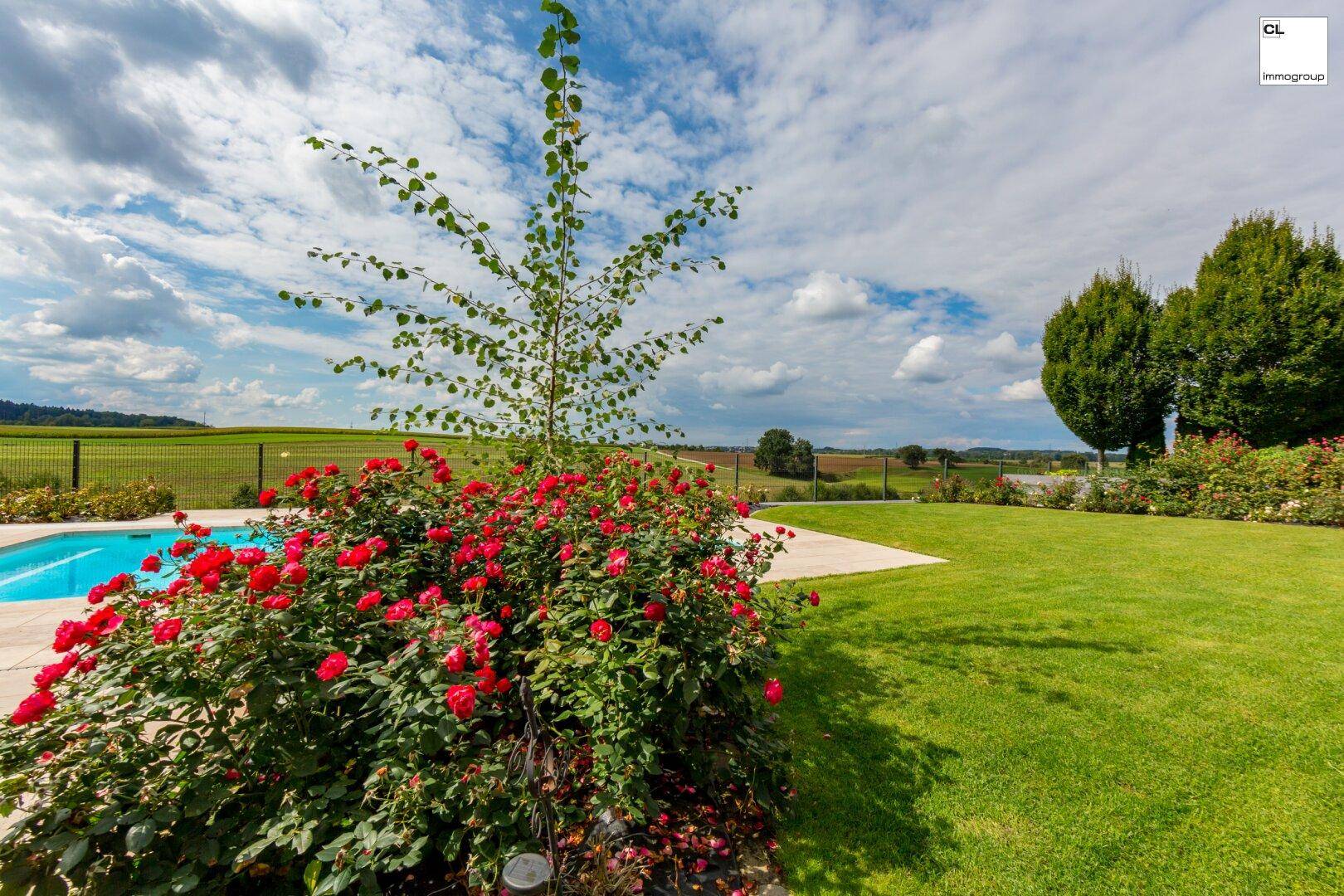 Gepflegter Gartenbereich mit Rosenbüschen, Rasenfläche und Blick auf die Landschaft.