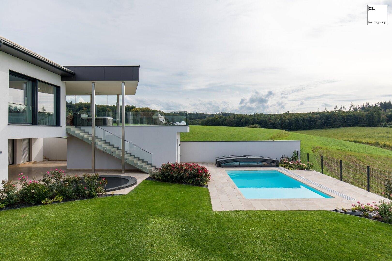Außenansicht der modernen Villa mit Pool, weitläufigem Garten und ländlichem Ausblick.