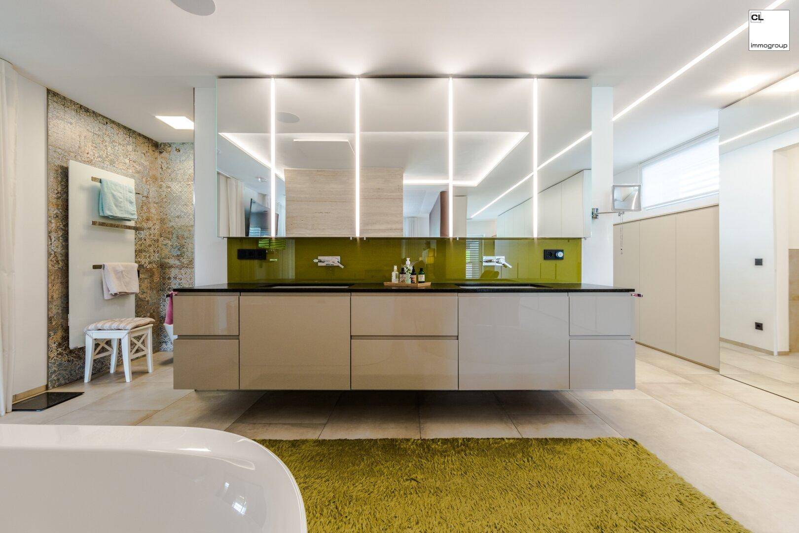 Luxuriöses Badezimmer mit Doppelwaschbecken, moderner Beleuchtung und freistehender Badewanne.