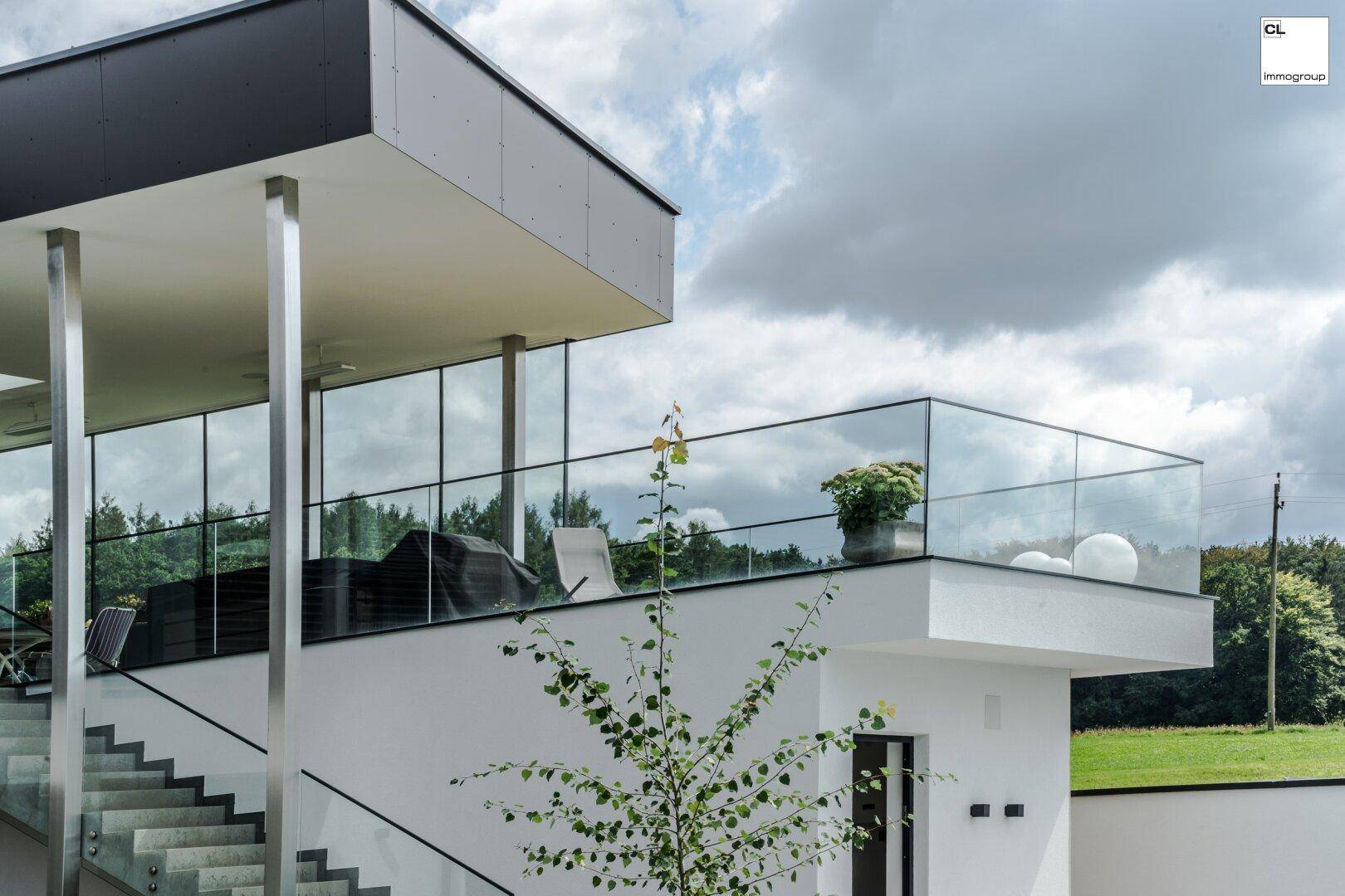 Elegante Dachterrasse mit Glasgeländer und weitem Blick in die Natur.