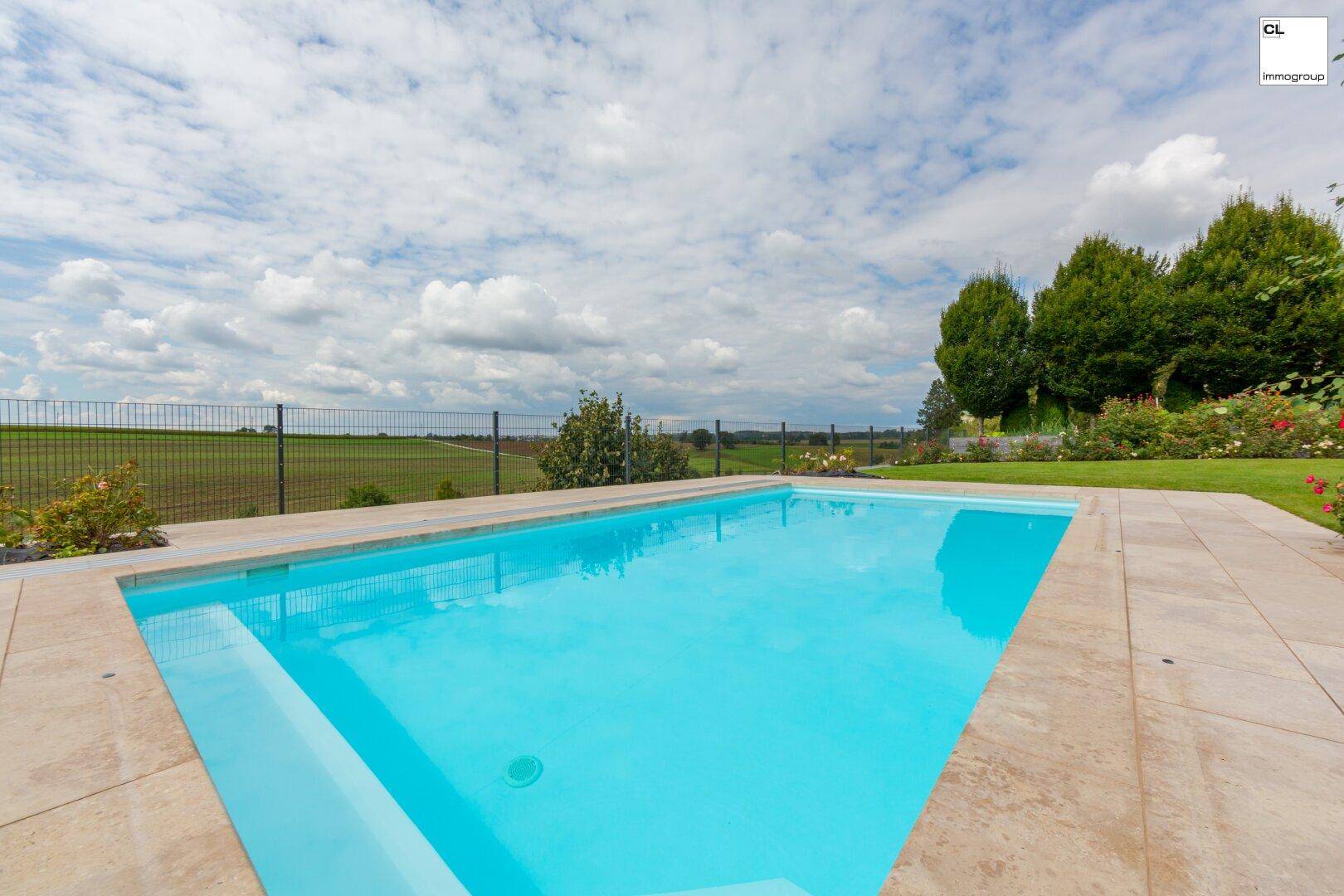 Nahaufnahme des Pools mit hellblauen Fliesen und weitem Blick über die Felder.