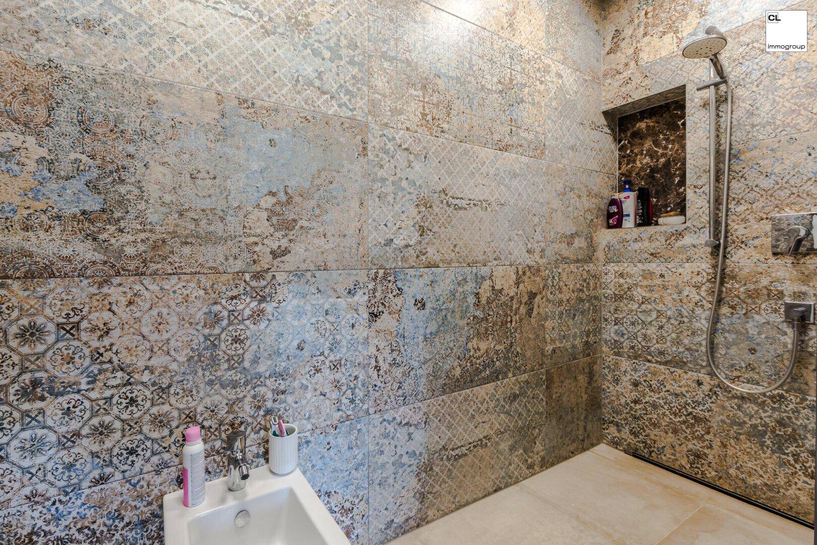 Badezimmer mit gemusterten Fliesen, moderner Duschkabine und Bidet.