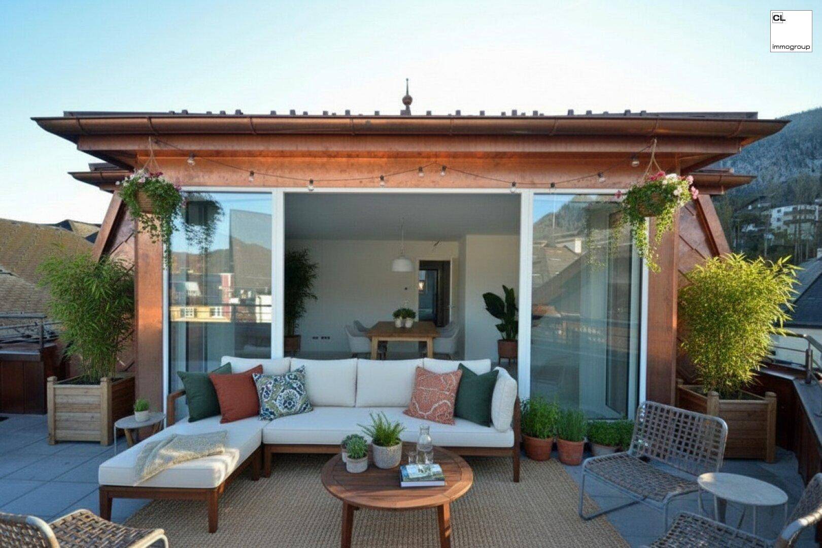 Gemütliche Dachterrasse mit bequemen Loungemöbeln, Pflanzen und Zugang zum Innenbereich.