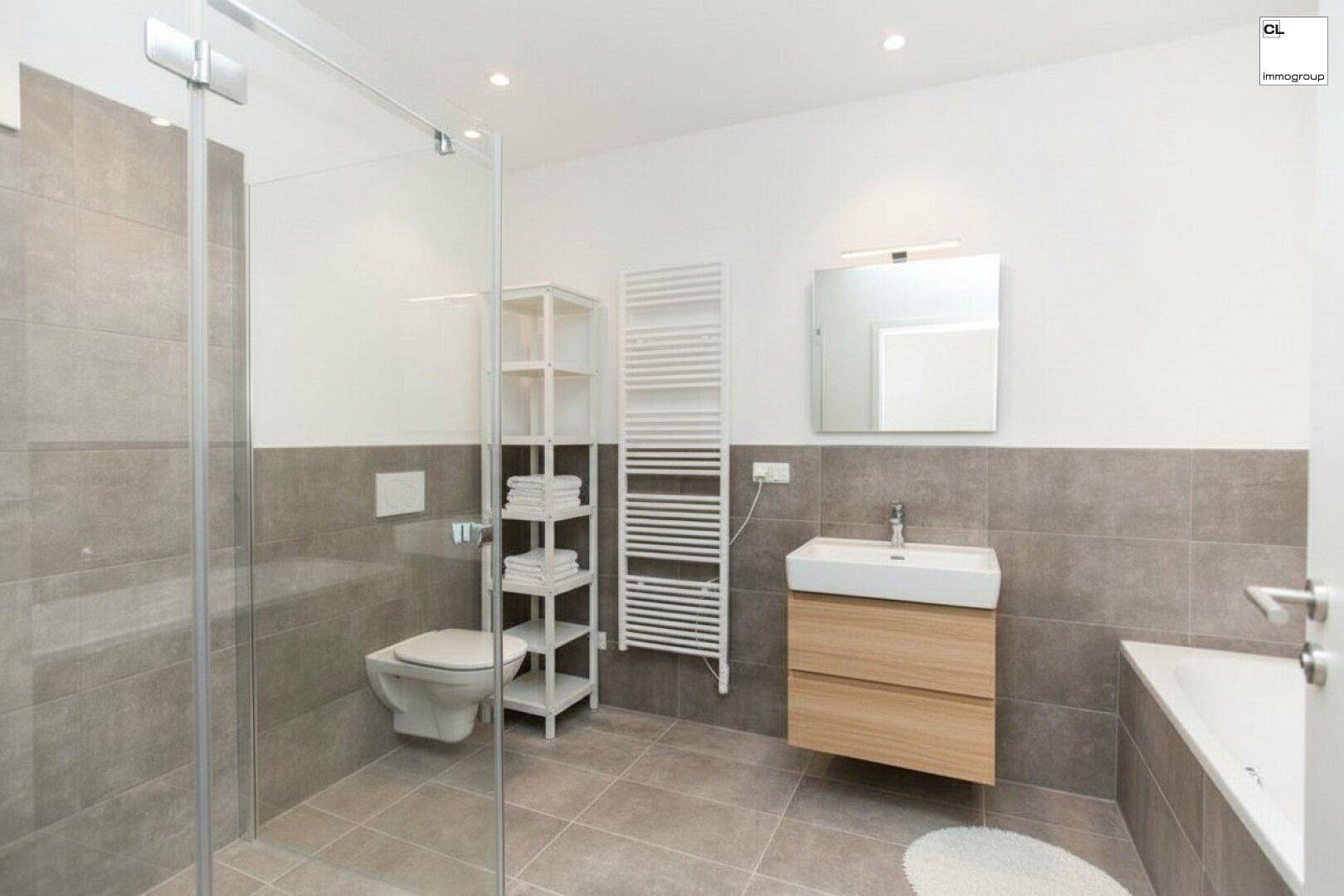 Helles Badezimmer mit WC, Waschtisch, Dusche und Badewanne, teilweise gefliest.