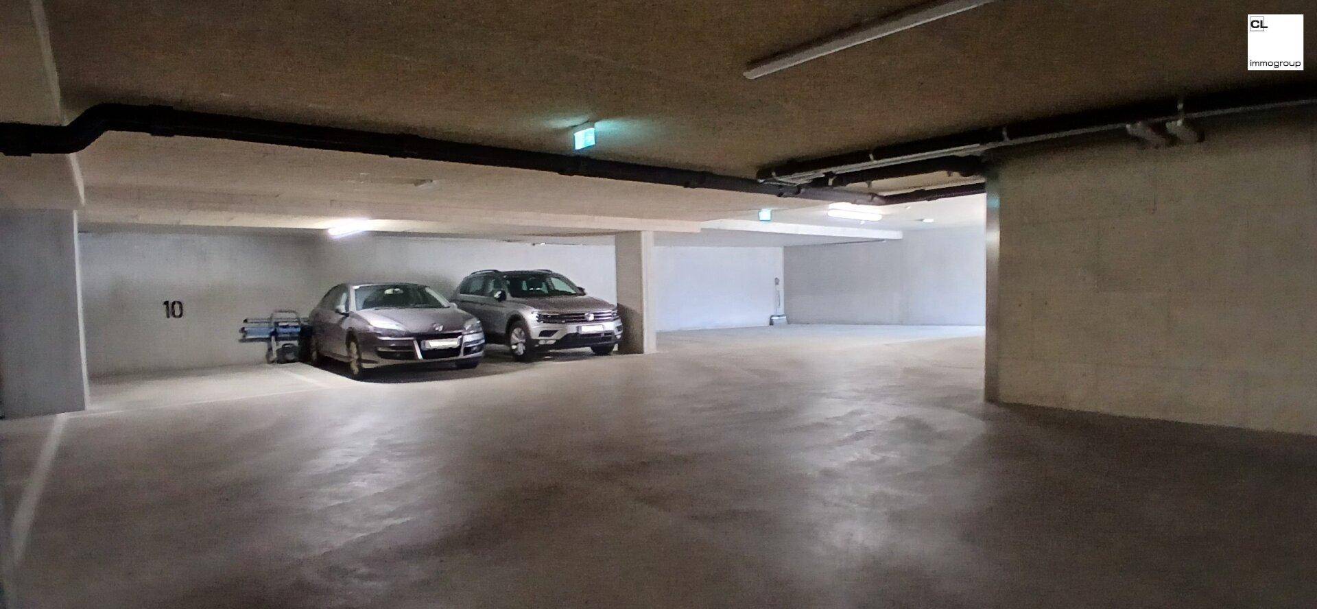 Helle Tiefgarage mit ausreichend Platz und einigen geparkten Fahrzeugen, sauber und ordentlich.