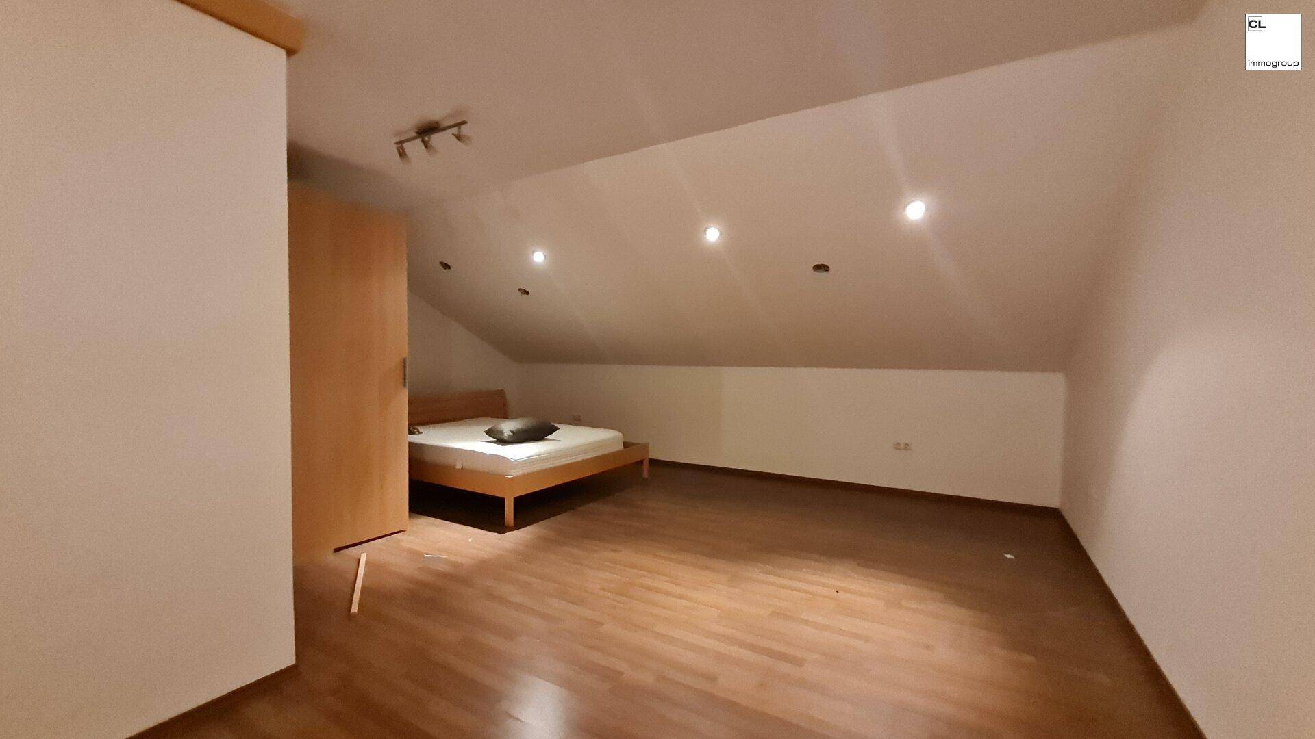 Schlafzimmer im Dachgeschoss mit schräger Decke, Holzboden und Einbaustrahlern.