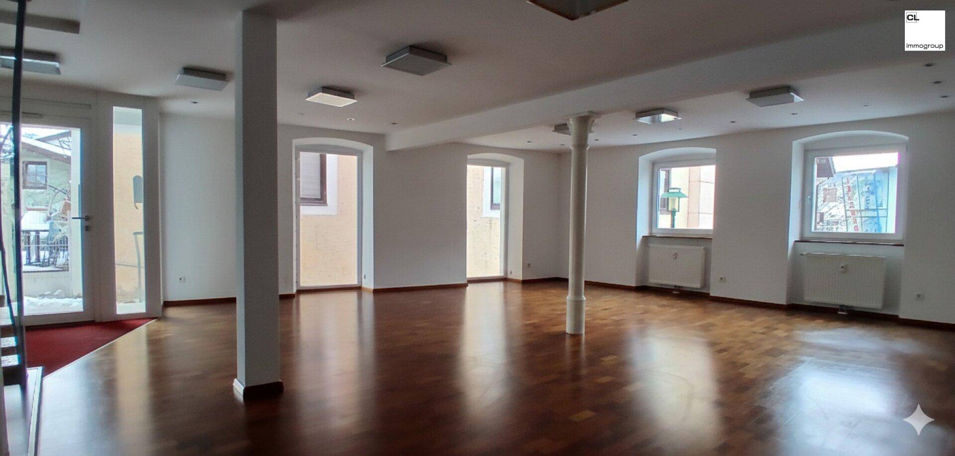 Heller, offener Raum mit Holzboden, mehreren Fenstern und Säulen, geeignet für verschiedene Geschäftskonzepte.