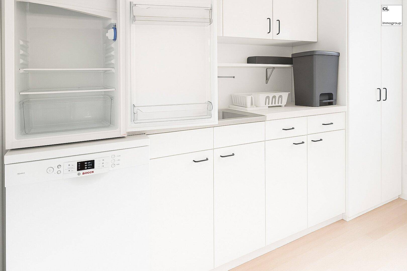 Moderne weiße Einbauküche mit Kühlschrank, Geschirrspüler und viel Stauraum.