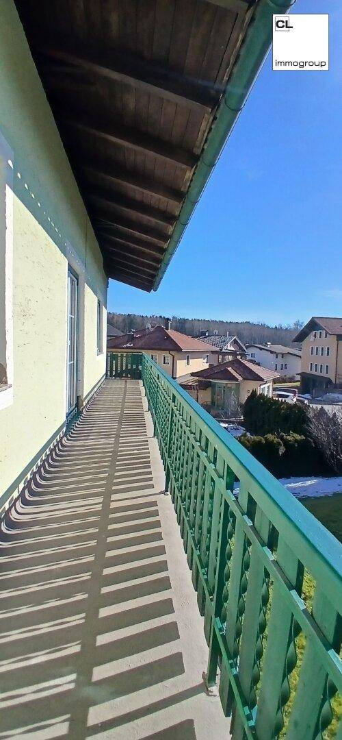 Langer Balkon mit grüner Brüstung und Blick auf die umliegende Wohnbebauung.