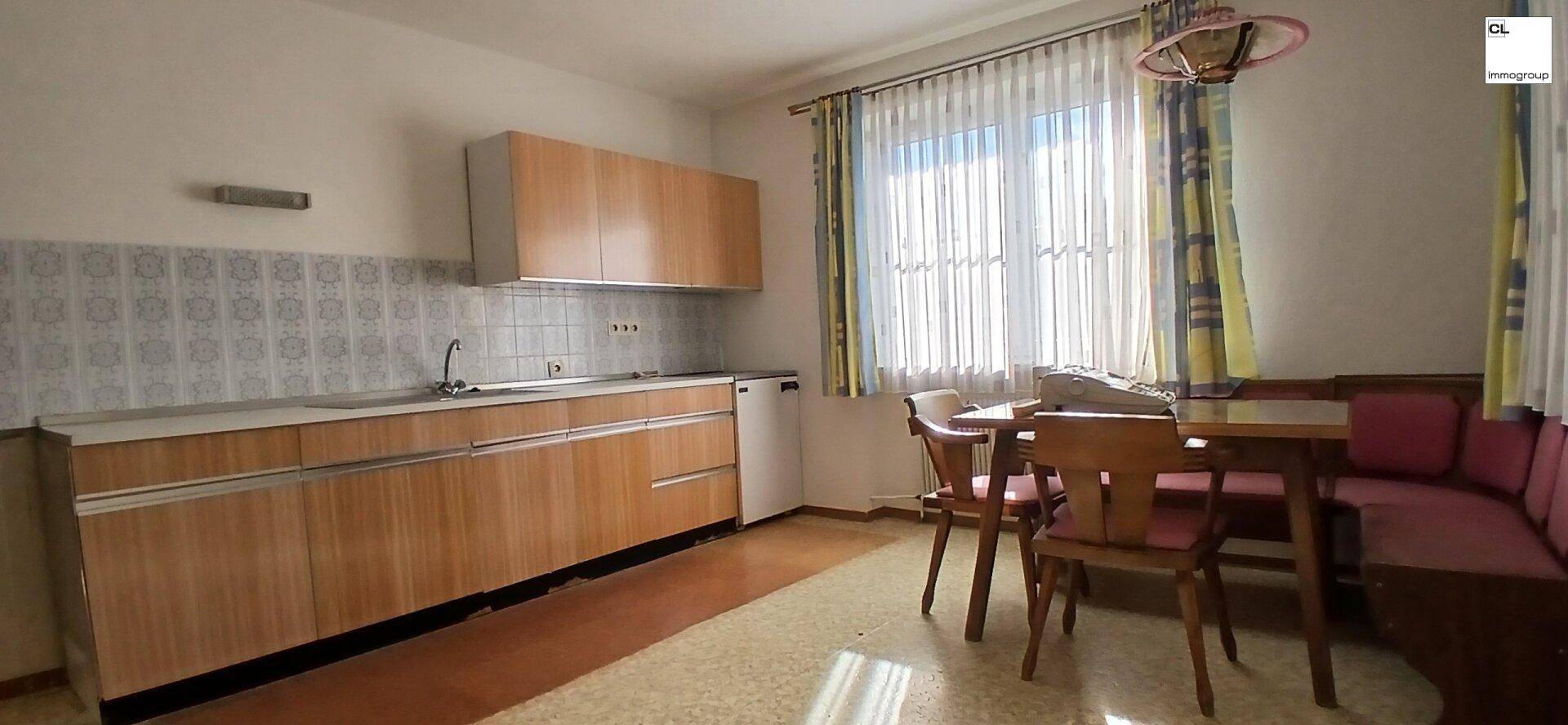 Funktionale Küche mit Holzschränken, gefliestem Spritzschutz und gemütlicher Essecke mit Eckbank.
