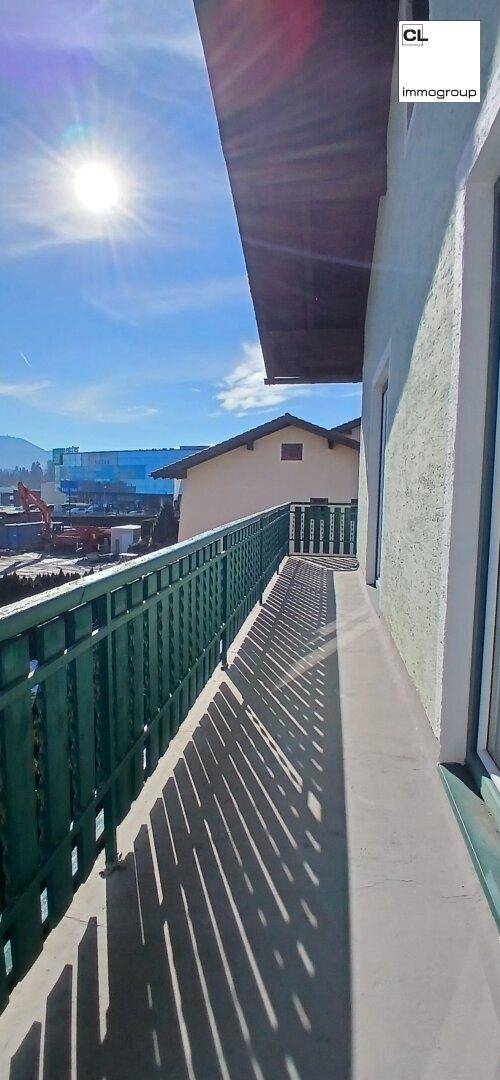 Sonniger Balkon mit grüner Brüstung und weitem Blick auf die Umgebung.