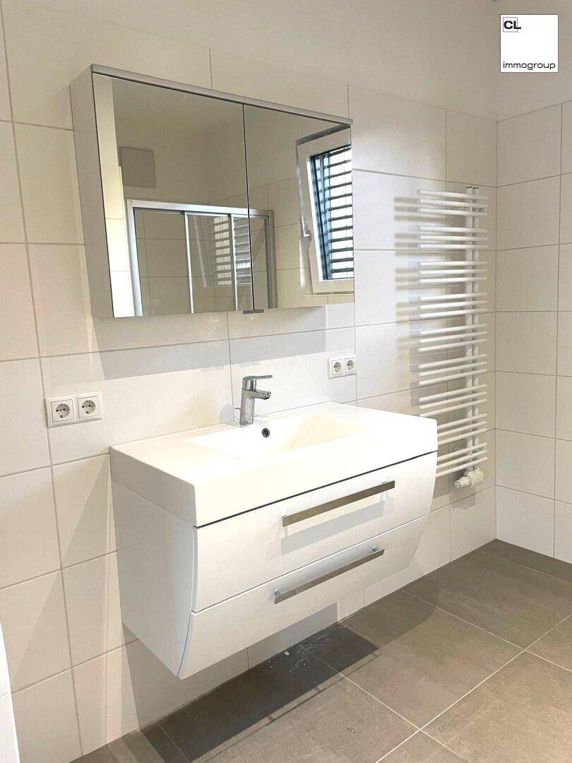 Modernes Badezimmer mit Waschtisch, Spiegelschrank und beheiztem Handtuchhalter.