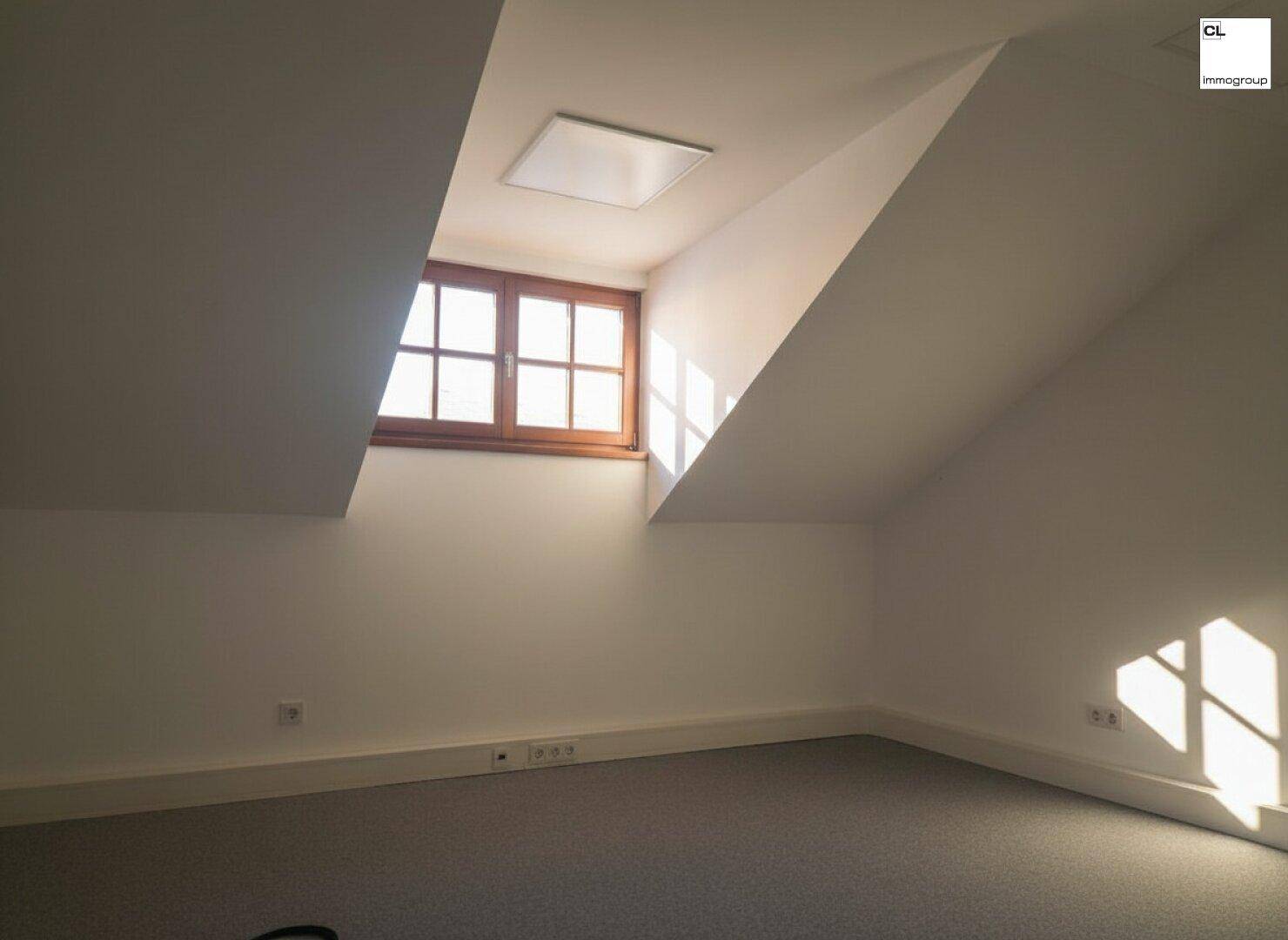 Dachgeschossraum mit Holzdachfenster und schrägen Wänden, ideal als kleines Büro oder Abstellraum.