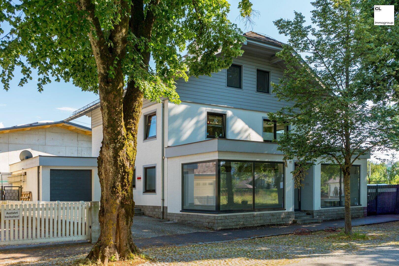Attraktives Haus mit weißer und grauer Fassade, großen Fenstern und einem Garagentor.
