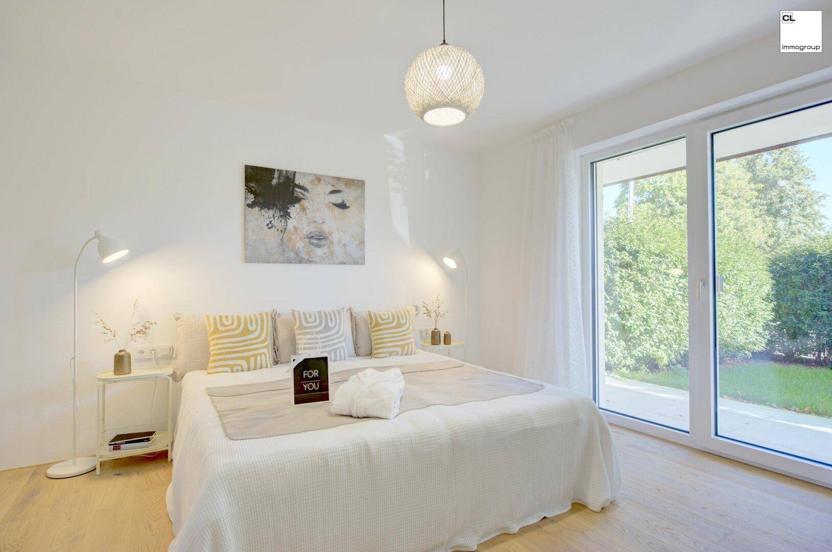 Helles Schlafzimmer mit Doppelbett, Holzboden und großen Fenstern mit Zugang zum Garten.