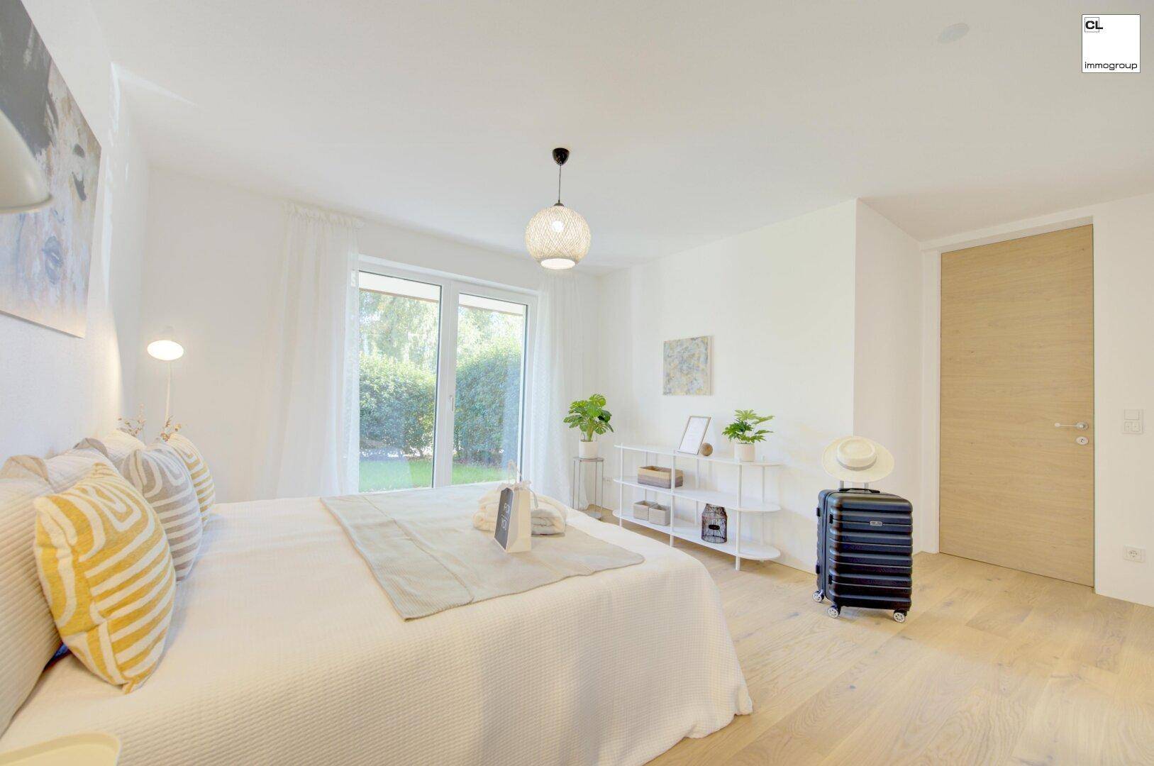 Modern eingerichtetes Schlafzimmer mit Holzboden, großen Fenstern und Blick ins Grüne.