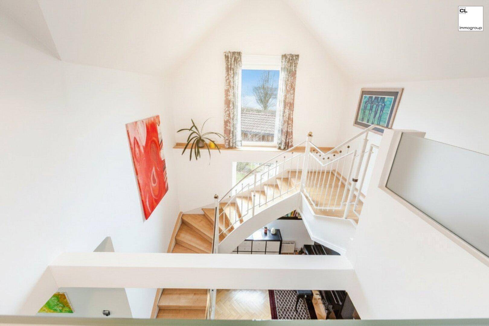 Blick von oben auf die helle Treppe mit Holzstufen und weißem Geländer, die mehrere Ebenen verbindet.
