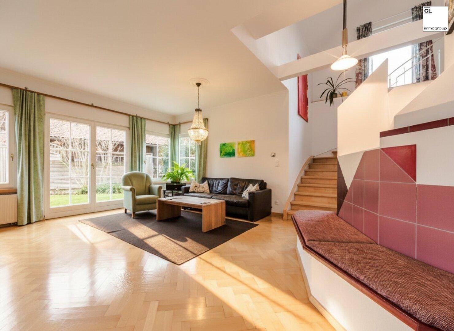 Helles Wohnzimmer mit Fischgrätparkett, bequemen Sofas und Zugang zum Garten durch große Fenster.