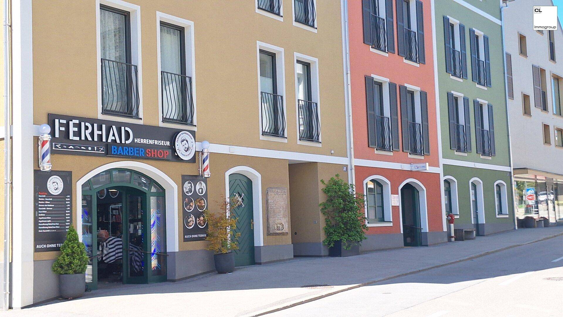 Nahaufnahme einer farbenfrohen Gebäudefassade mit einem Friseursalon im Erdgeschoss.